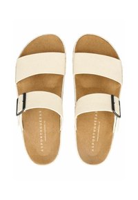 Béžové plátěné sandály se dvěma širokými pásky, černým sponovým akcentem a měkkou hnědou stélkou. Plochý design s texturovanou podrážkou.