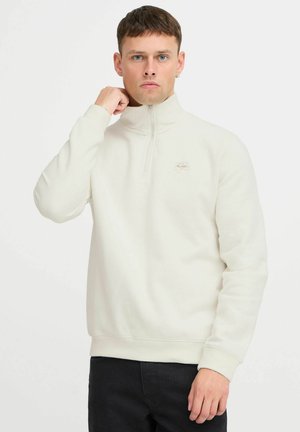 Helle cremfarbene Zip-up Sweatjacke, weicher Stoff, gerippte Bündchen und Saum, mit einem kleinen gestickten Logo in kontrastierender Farbe auf der Brust.