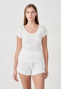 Witte T-shirt met korte mouwen en een ronde nek, versierd met een textuurpatroon, gecombineerd met bijpassende shorts met scalloped randen.