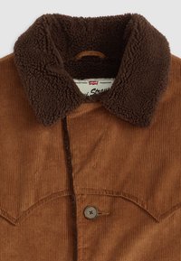 Chaqueta de pana marrón con un cuello de sherpa marrón oscuro, cierre de botones y tejido texturizado, que presenta una etiqueta distintiva de Levi's en su interior.