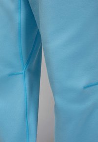 Jasnoniebieskie spodnie sportowe o miękkiej fakturze, smukłym kroju i kontrastowym przeszyciu wzdłuż szwów, co zapewnia schludne wykończenie.