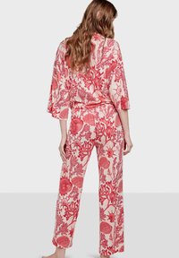 Conjunto de dos piezas con estampado floral que incluye una blusa holgada con mangas amplias y pantalones de pierna ancha. Los colores incluyen rojo y crema.