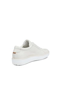 Sneaker bianca in pelle con finitura testurizzata, punta rotonda, suola piatta in gomma bianca e un sottile accento beige sul tallone.