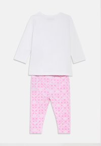 Λευκό πουκάμισο μακρυμάνικο με στρογγυλή λαιμόκοψη, συνδυασμένο με ροζ κολάν με γεωμετρικά σχέδια και διακριτικές λεπτομέρειες λογότυπου.