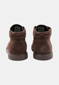 Bottines en daim marron avec un bout arrondi, texture douce, tirette à l'arrière et semelle en caoutchouc solide. Conçues avec un minimum de détails de couture.