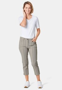Witte, kortekleding met korte mouwen gecombineerd met lichtgrijze gestreepte enkellange broeken. De broeken hebben een knoopsluiting aan de voorkant en zijzakken. Witte sneakers worden gedragen.