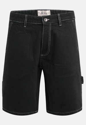 Pantalones cortos negros hasta la rodilla con costuras blancas, trabillas para cinturón, cierre de botón y un detalle de anillo para herramientas en el lateral, con la etiqueta "REBEL" en el interior de la cintura.