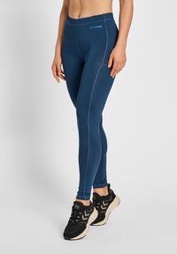 Marina blå leggings med en slät textur, med kontrasterande sömmar och en åtsittande design. Logotypdetalj på midjebandet. Svarta sportskor.