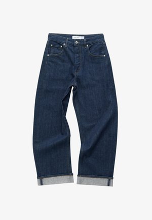 Dark blue denim jeans with a relaxed fit, folded cuffs, five-pocket design, and subtle orange stitching. Features a brand label at the waist.
