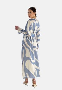 Lungo vestito blu e bianco con motivo a fantasia, design avvolgente, maniche lunghe e una cintura in vita. Tessuto morbido ed elegante silhouette.