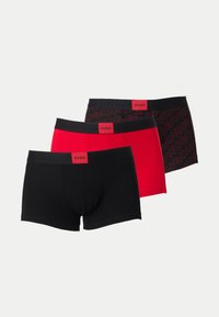 Trois boxers pour hommes en noir, rouge et noir avec motif logo rouge, chacun avec une ceinture noire et une étiquette rouge portant la mention HUGO.