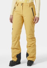 Gele waterdichte sneeuwbroek met zwarte onderaccenten, ritszakken en een gestructureerde pasvorm. Gemaakt van duurzaam materiaal voor winteractiviteiten.