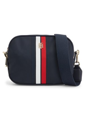 Sac bandoulière bleu marine avec large bandoulière réglable, rayures verticales rouges, blanches et bleu marine, et logo en métal doré à l'avant.