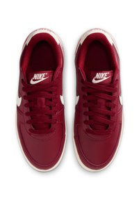 Rode leren sneakers met witte accenten, vetersluiting, ronde neus en een getextureerde binnenkant, met het kenmerkende Nike-logo op de tong.