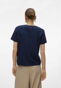 Marineblå bomulds T-shirt med en afslappet pasform, korte ærmer og rund halsudskæring, parret med lysebeige bukser.
