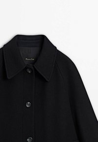 Manteau en laine noir avec col pointu et trois boutons noirs visibles à l'avant, montrant le haut du torse et la zone des épaules.