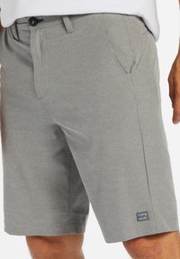 Shorts gris texturé avec fermeture à bouton sur le devant, deux poches latérales et un petit logo cousu en bas. Design décontracté, taille au genou.