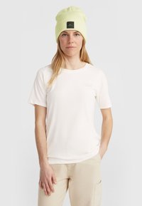 Lichtroze T-shirt met korte mouwen en een ronde halslijn, voorzien van een subtiele logo op de borst, gecombineerd met een fel limoen groene beanie met een patch.
