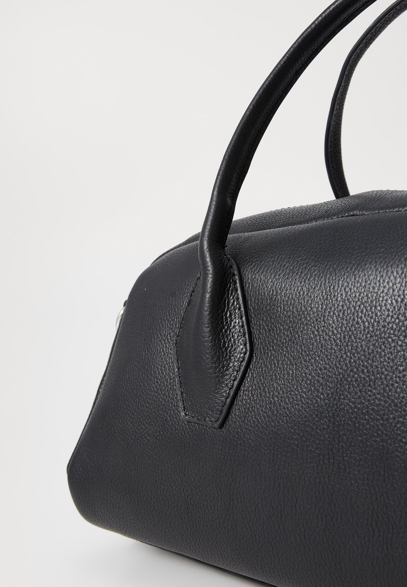 Bolsa de couro preta com superfície texturizada, forma arredondada e duas alças resistentes. Acentuada com um detalhe hexagonal na lateral.