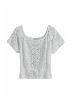 White short-sleeve knit top with diamond-patterned lace, scoop neckline, and a tie at the waist.