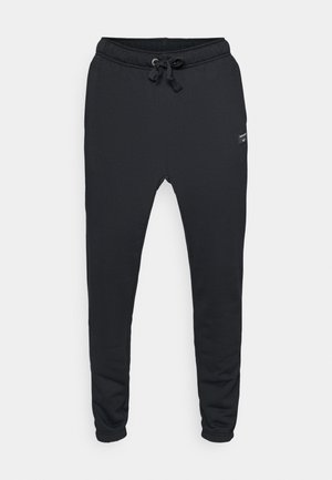 Schwarze Jogginghosen mit elastischem Bund, verstellbarem Kordelzug und Seitentaschen. Weicher Stoff mit glatter Textur und schmal zulaufenden Beinen.