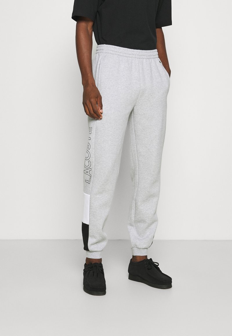 Gray sweatpants made of soft material with an elastic waistband, featuring black and white accents and a logo on the side.