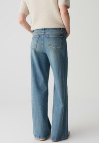 Jeans ampi di colore azzurro chiaro con vita alta e tasche a toppa doppie sul retro. Realizzati in denim, presentano una leggera scoloritura e dettagli di cucitura.