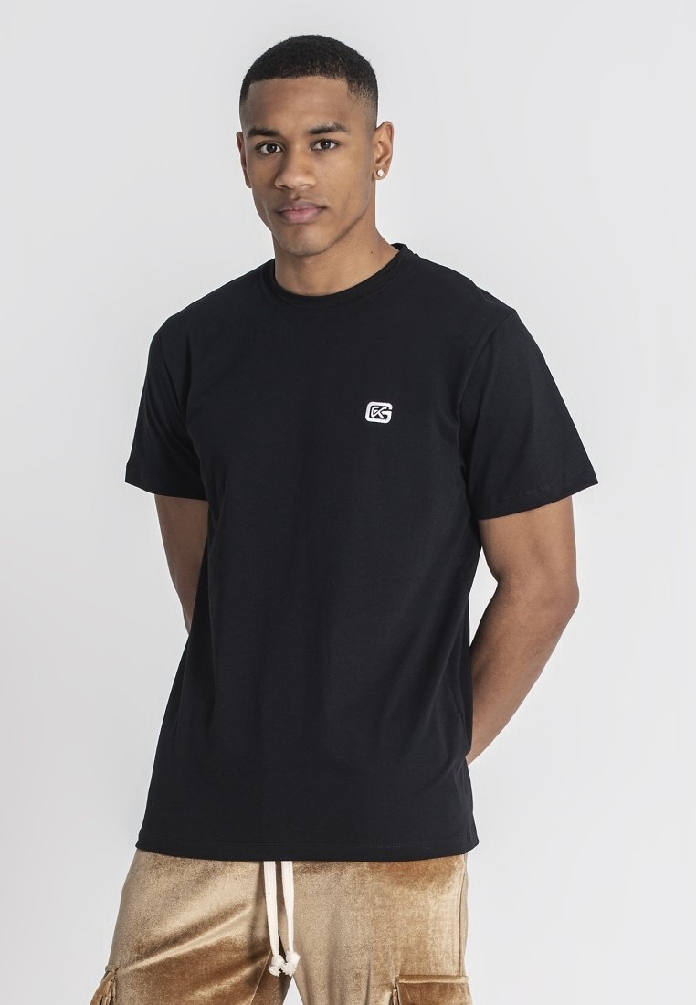 Camiseta de algodón negra con escote redondo y mangas cortas. Presenta un pequeño logotipo blanco en la parte izquierda del pecho. Diseño simple y clásico.