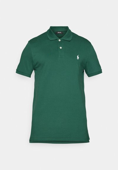 Tumši zaļš polo krekls, kas izgatavots no gludas kokvilnas, ar apkakli, trim pogām un mazu baltu logo kreisajā krūtī. Īsas piedurknes.