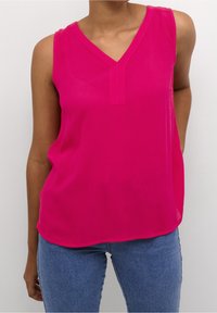 Haut sans manches fuchsia avec un col en V, fabriqué dans un tissu léger. Présente une texture subtile et une coupe décontractée.