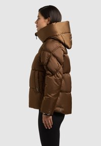 Braune Steppjacke mit hohem Kragen, glänzender, gesteppten Oberfläche, horizontalen Kammern und einer seitlichen Reißverschlusstasche.