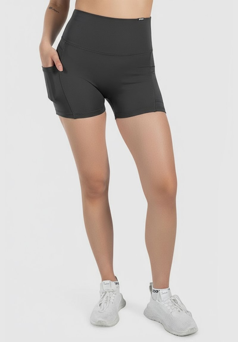 Shorts sportivi neri a vita alta realizzati in tessuto elastico, con tasche laterali e un design aderente e liscio. Abbinati a scarpe sportive bianche.