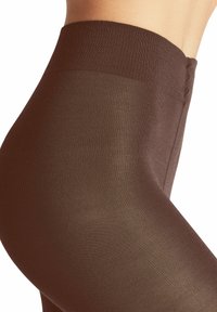Collants marron avec une finition lisse et mate et une taille élastique. La texture est douce et légèrement transparente, avec des détails côtelés subtils.