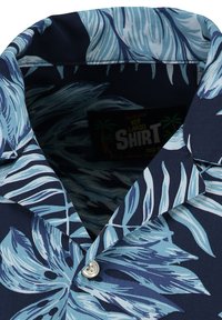 Korte mouwen shirt met een marineblauwe achtergrond en grote lichtblauwe bladdessins, platte kraag en een witte knoopsluiting.