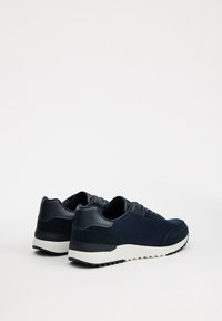 Zapatillas deportivas azul marino con parte superior de malla texturizada, acentos sintéticos suaves y una suela de goma blanca con un patrón estriado.