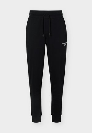 Čierne zúžené tepláky s elastickým pásom, šnúrkou, manžetami na členkoch a malým bielym logom "Björn Borg" na hornej časti stehna.