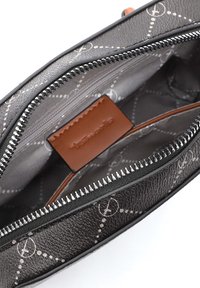 Black patterned zippered bag open to show gray interior lining and brown leather brand tag.