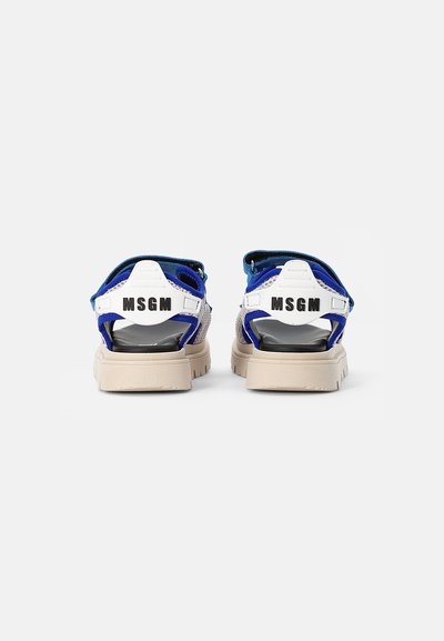 Vista traseira de sandálias azul e branca com sola espessa bege. Apresenta tiras ajustáveis e o logótipo "MSGM" na parte de trás em preto.