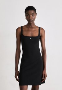 Black sleeveless dress with a square neckline, made from a smooth fabric. Features a small logo at the chest and a fitted silhouette.
