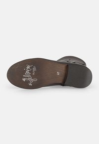 Sola di scarpa in pelle nera con una finitura testurizzata, caratterizzata da marchiatura in rilievo e dettagli sulla taglia. Bordo liscio e scuro con curve sottili.