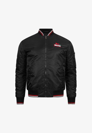 Chaqueta bomber negra de satén con acentos a rayas rojas y blancas en el cuello y los puños, con un logo en el pecho y bolsillos laterales.