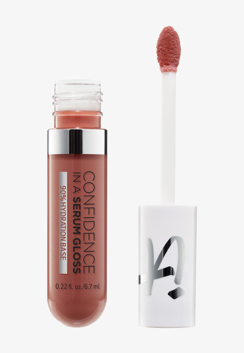 Lippenserum-Gloss-Tube mit der Aufschrift "Confidence in a Serum Gloss" und Applikatorstab, der einen rosé-nude-farbenen Gloss an der Spitze zeigt.