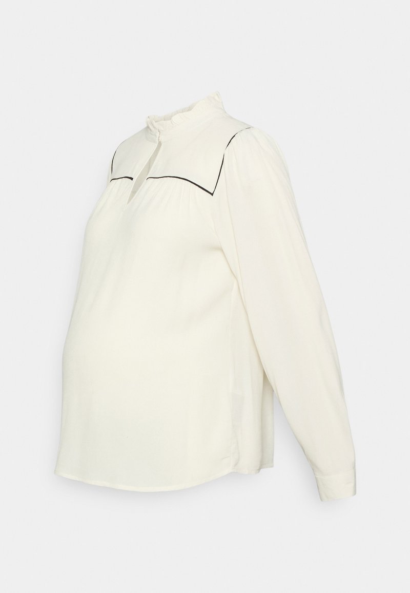 Blusa de mangas longas em tom creme com um colarinho franzido e detalhes em preto ao longo da peça. Apresenta um corte confortável e solto.