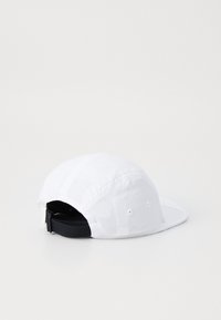 Hvit baseballcaps med flat brem, laget av lett materiale. Har en svart justerbar stropp bak og ventilasjonshull.