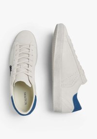 Zapatillas de ante blancas con suela de goma plana, con un acento de ante azul en el talón y cordones centrales. Detalles perforados en los laterales.