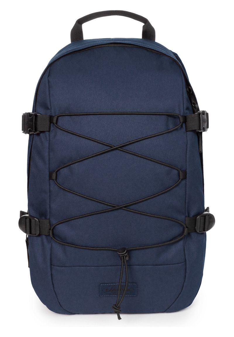 Mochila azul marino con un tejido texturizado, que presenta un sistema de cordones en la parte frontal, dos hebillas laterales y una asa superior para llevar.