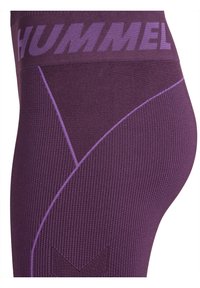 Lila leggings med ribbad struktur som har en bred midje med "HUMMEL"-logotyp och kontrasterande violetta sömmar, designade i en figurnära stil.