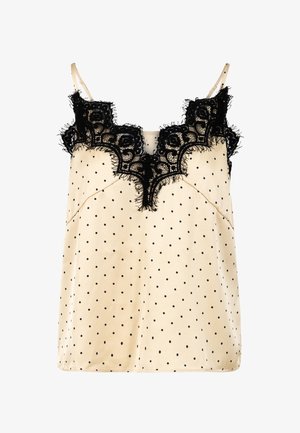 Camisole crème à pois noirs, bordure en dentelle noire au niveau de l'encolure et fines bretelles réglables.