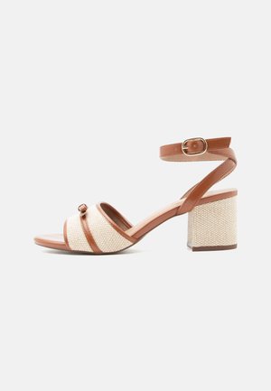 Barna és bézs blokk sarkú szandál bokapánttal és texturált szövet felsőrésszel, nyitott orr kialakítású, arany színű csattal záródik.