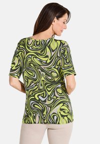 T-shirt à manches courtes avec un motif tourbillonnant vert et gris, fabriqué en tissu léger, avec un col rond et une coupe décontractée.